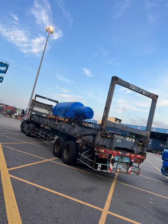 圓筒狀機械設備以防水布包覆並綁紮於 40 呎平板貨櫃